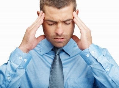 A picture of a man looking stressed and holding his hands to his head